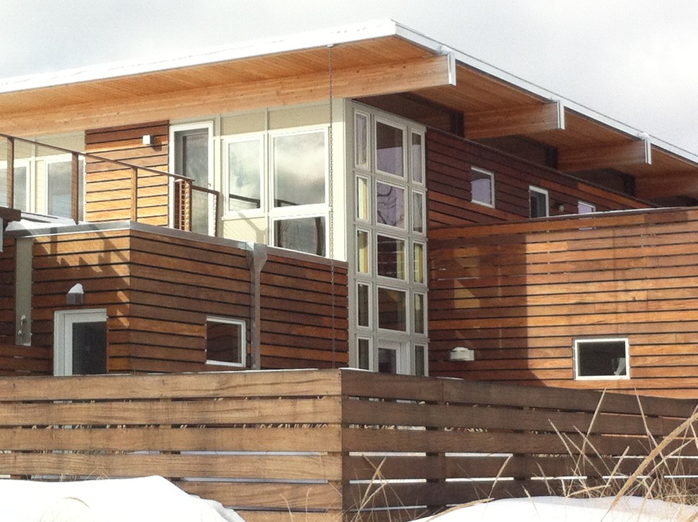 Foto della facciata di una casa grande marrone contemporanea a due piani con rivestimento in legno e tetto piano
