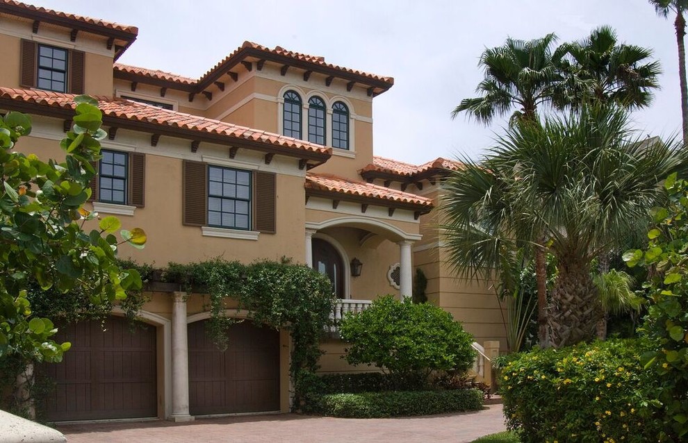 Example of a large southwest beige two-story stucco house exterior design in Tampa with a hip roof and a tile roof