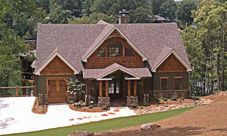 Ejemplo de fachada marrón rústica de tamaño medio de dos plantas con revestimientos combinados