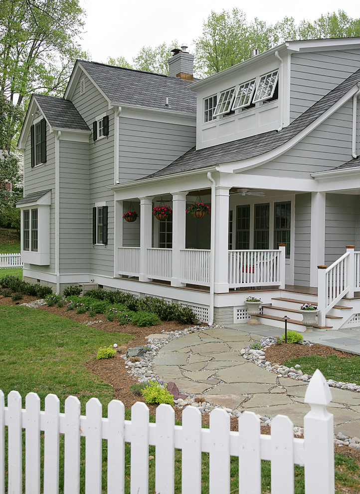 Aménagement d'une grande façade de maison grise classique en panneau de béton fibré à un étage avec un toit à deux pans.