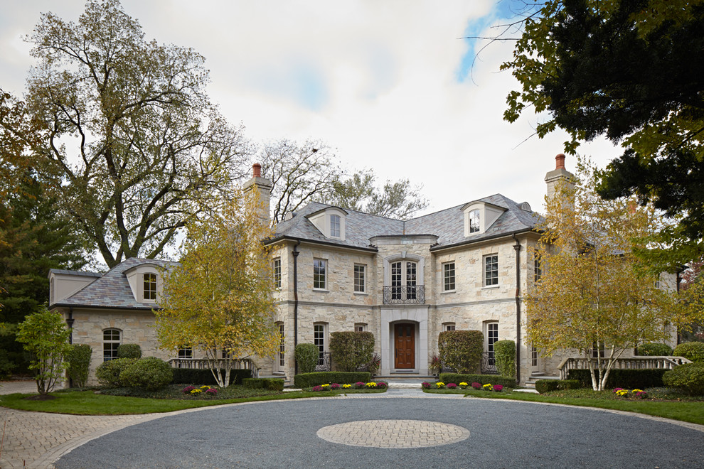 Immagine della facciata di una casa grande beige classica a due piani con rivestimento in pietra