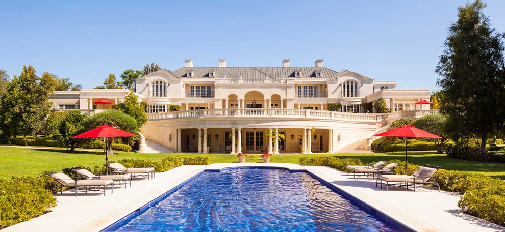 Cette photo montre une très grande façade de maison beige méditerranéenne en pierre à deux étages et plus avec un toit à deux pans.