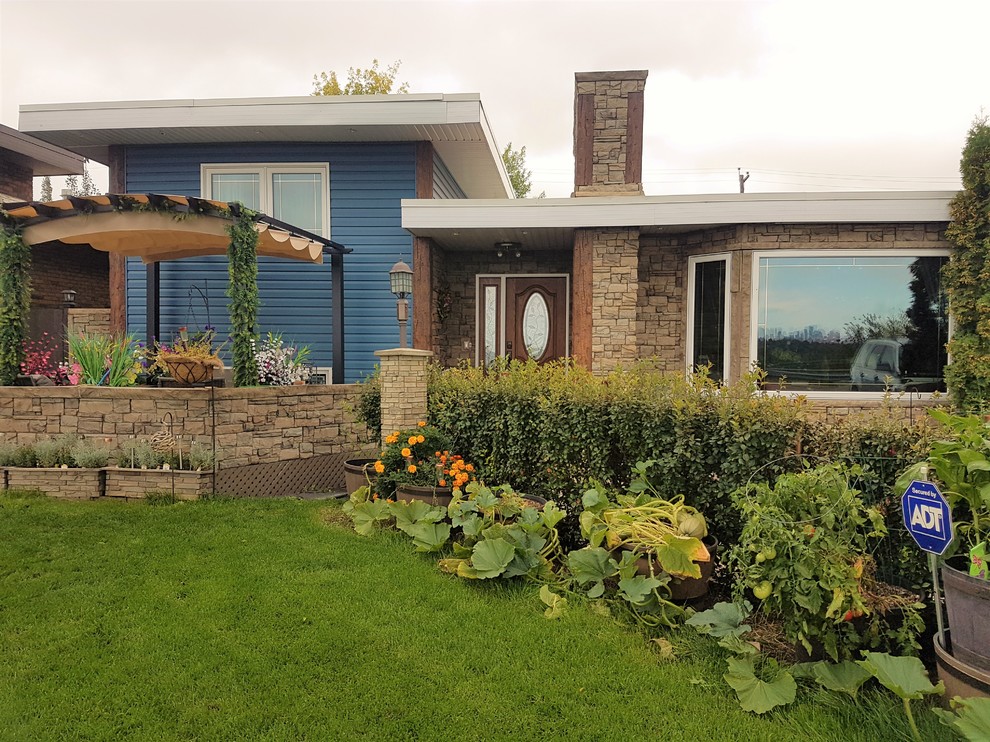 Diseño de fachada de casa azul tradicional renovada de tamaño medio a niveles con revestimiento de vinilo y tejado plano