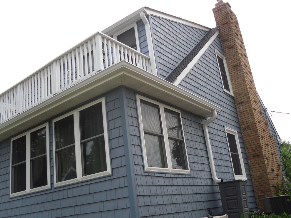 На фото: маленький, двухэтажный, синий дом в морском стиле с облицовкой из винила для на участке и в саду