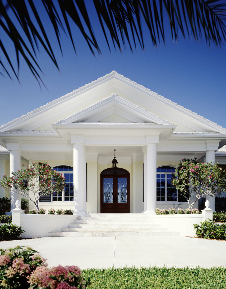 Foto della facciata di una casa bianca tropicale a un piano di medie dimensioni con rivestimento in stucco e tetto a capanna