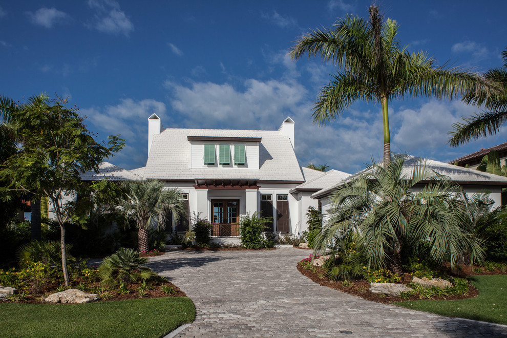 Foto della facciata di una casa piccola bianca tropicale a due piani con rivestimento in stucco e tetto a padiglione