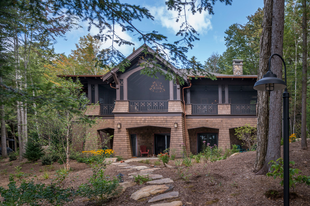 Imagen de fachada de casa marrón rural grande de dos plantas con revestimiento de madera, tejado a cuatro aguas y tejado de teja de madera