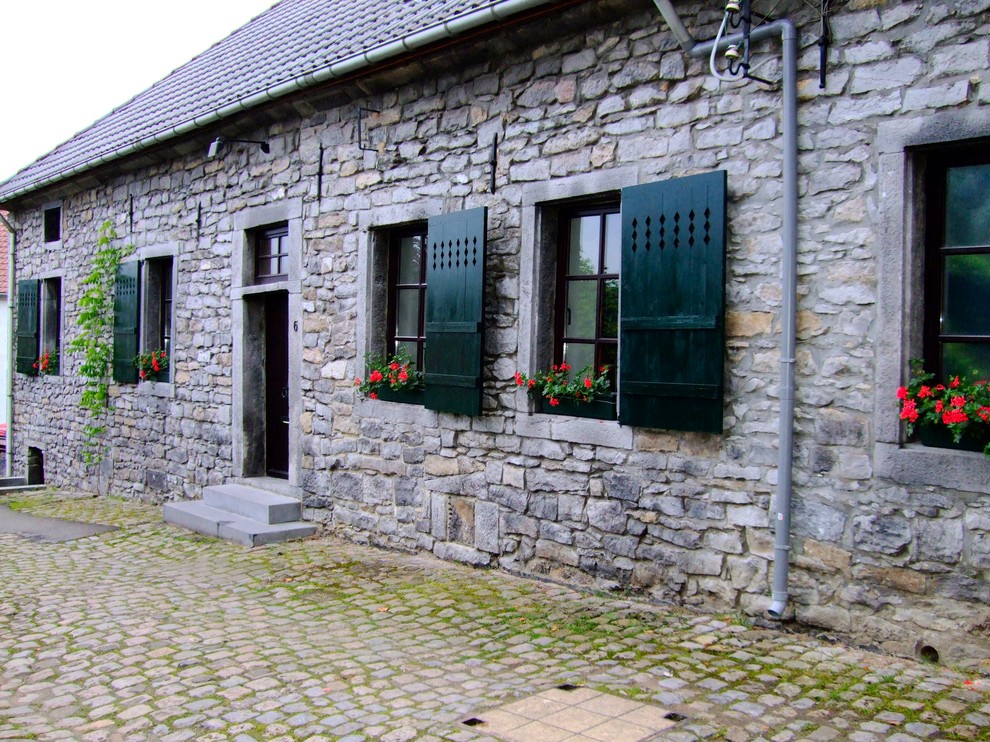 Esempio della facciata di una casa country a un piano di medie dimensioni con rivestimento in pietra
