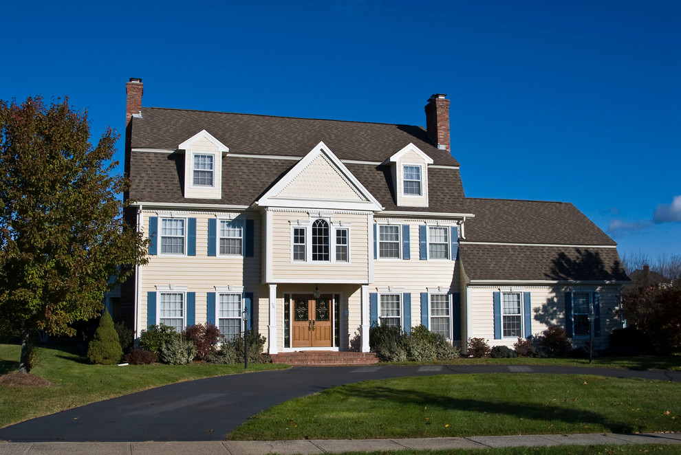 Large elegant yellow three-story wood house exterior photo in Bridgeport with a gambrel roof and a shingle roof