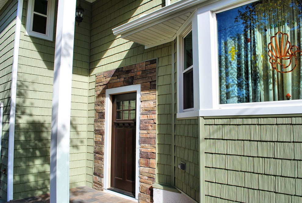 Cette photo montre une façade de maison verte chic de taille moyenne et à niveaux décalés avec un revêtement mixte et un toit à quatre pans.