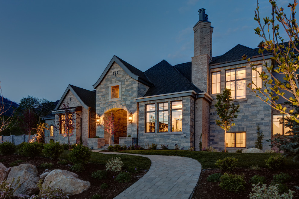 Large traditional beige three-story stone house exterior idea in Salt Lake City with a shingle roof and a clipped gable roof