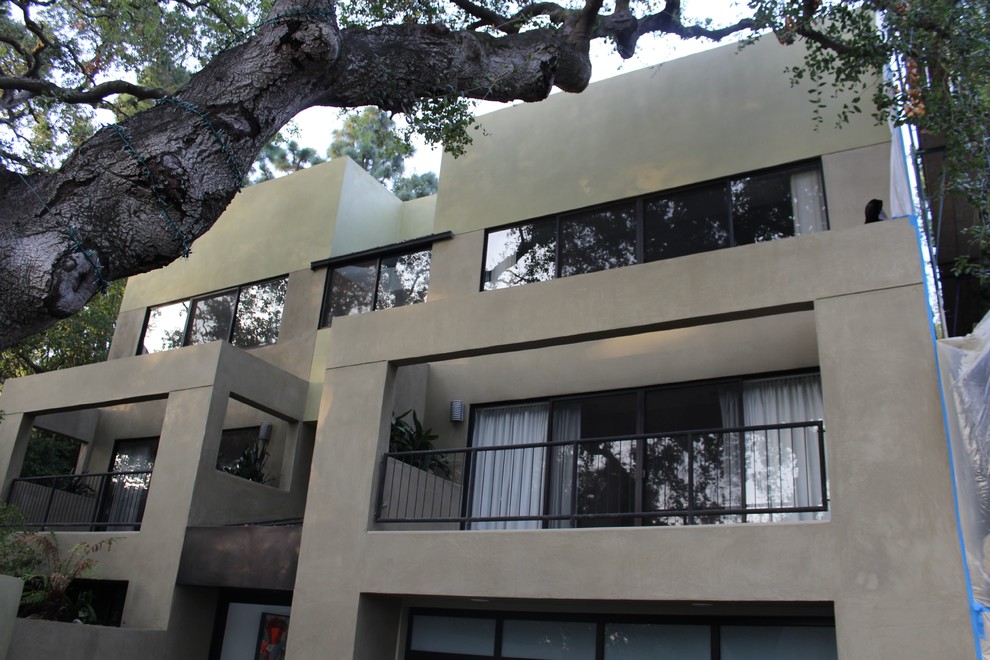 Esempio della facciata di una casa verde contemporanea a tre piani con rivestimento in stucco e tetto piano