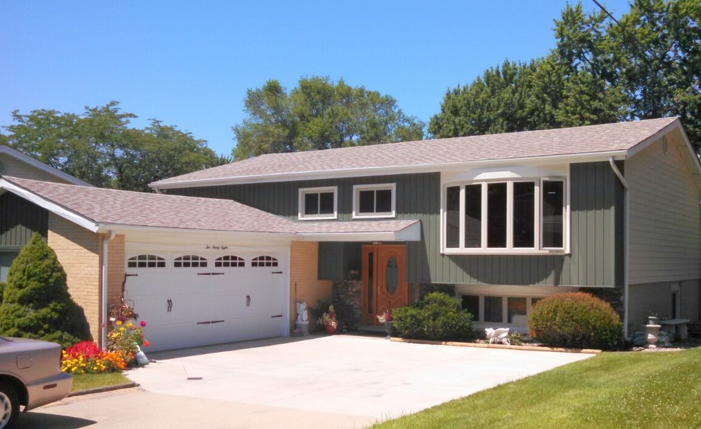 Large mid-century modern green two-story vinyl gable roof idea in Chicago