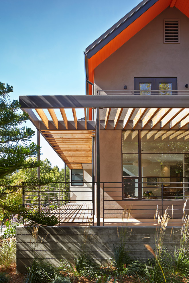 Réalisation d'une grande façade de maison marron design en stuc à deux étages et plus avec un toit à deux pans.