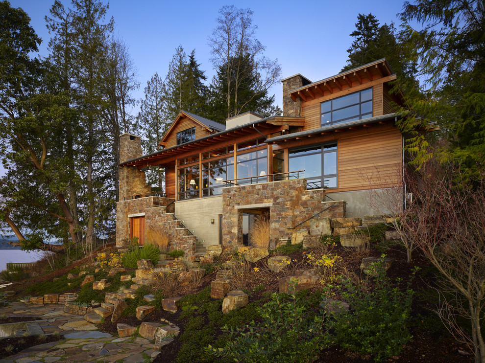 This is an example of a large and brown rustic detached house in Seattle with wood cladding, three floors, a pitched roof and a metal roof.