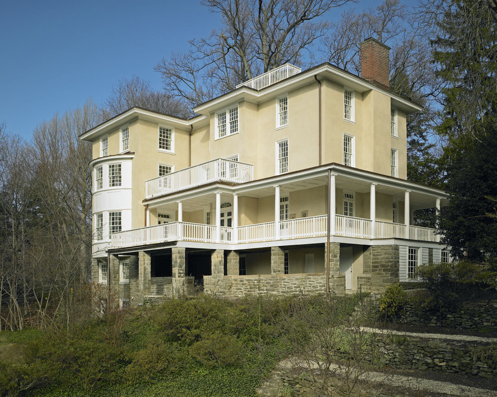 Immagine della facciata di una casa gialla classica a tre piani con rivestimento in stucco e tetto piano