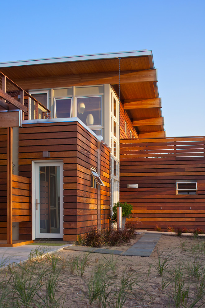 Diseño de fachada marrón actual grande de dos plantas con revestimiento de madera y tejado plano