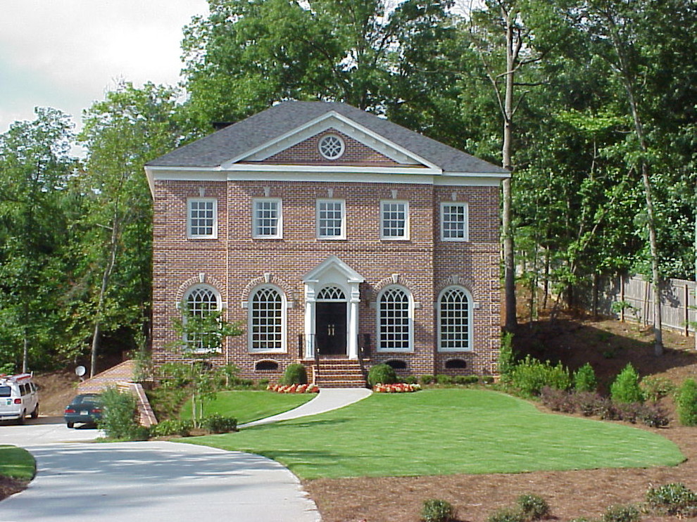 Cette image montre une très grande façade de maison rouge traditionnelle en brique à un étage avec un toit à deux pans.