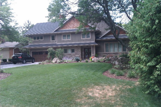 Imagen de fachada gris de estilo americano de tamaño medio a niveles con revestimientos combinados y tejado a dos aguas