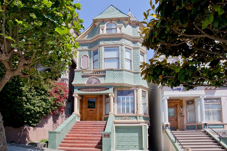 Пример оригинального дизайна: трехэтажный, деревянный, большой, разноцветный дом в викторианском стиле с двускатной крышей