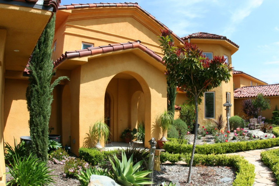 Источник вдохновения для домашнего уюта: большой, двухэтажный, желтый частный загородный дом в средиземноморском стиле с облицовкой из камня, вальмовой крышей и черепичной крышей
