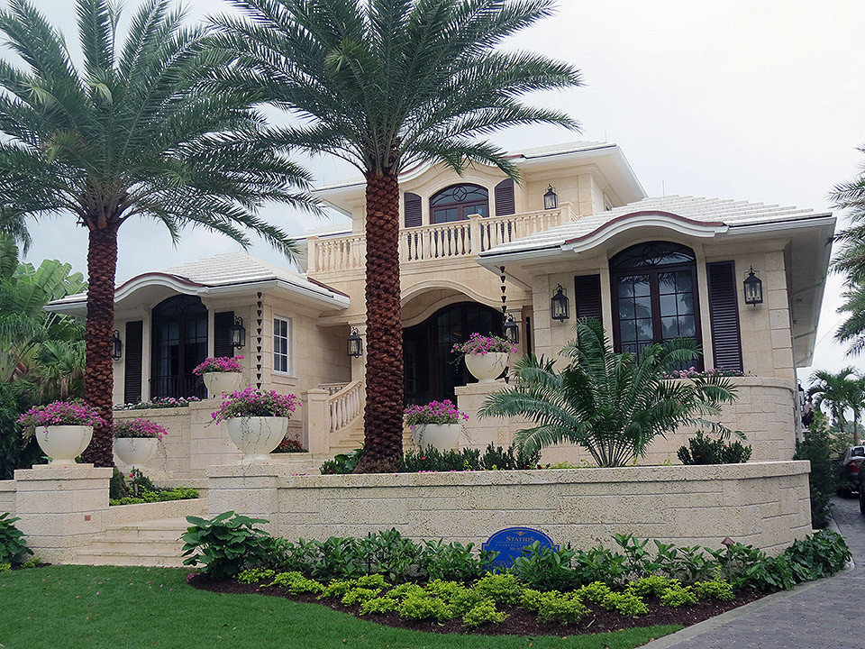 This is an example of a large and beige mediterranean two floor house exterior in Miami with mixed cladding.