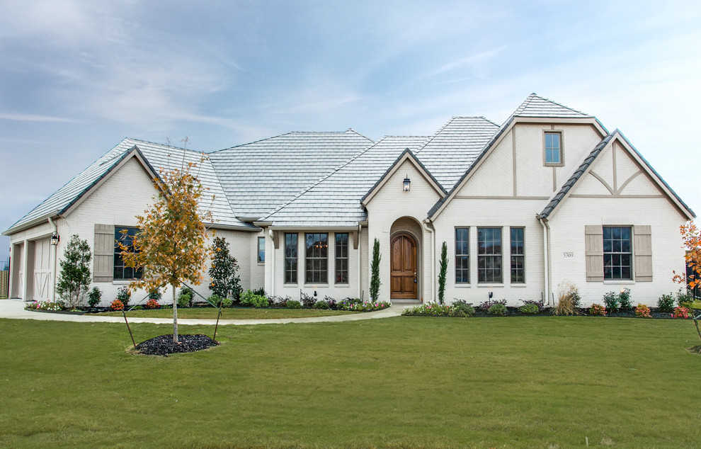 Large elegant white two-story brick exterior home photo in Dallas with a clipped gable roof