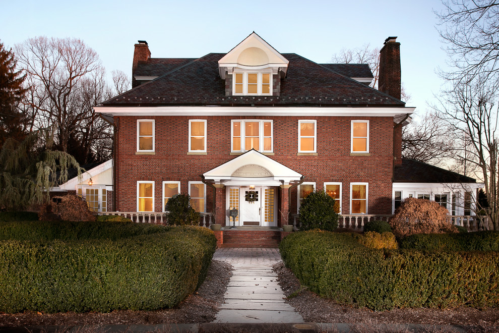 На фото: двухэтажный, кирпичный, красный дом в классическом стиле с вальмовой крышей
