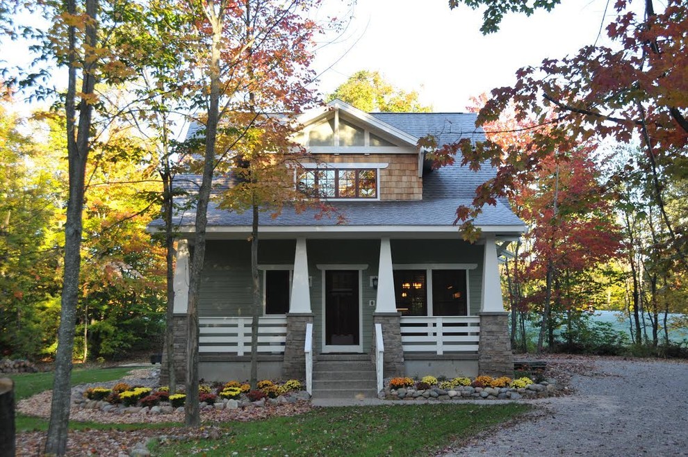 Modelo de fachada de casa verde de estilo americano de tamaño medio de dos plantas con revestimiento de vinilo, tejado a dos aguas y tejado de teja de madera