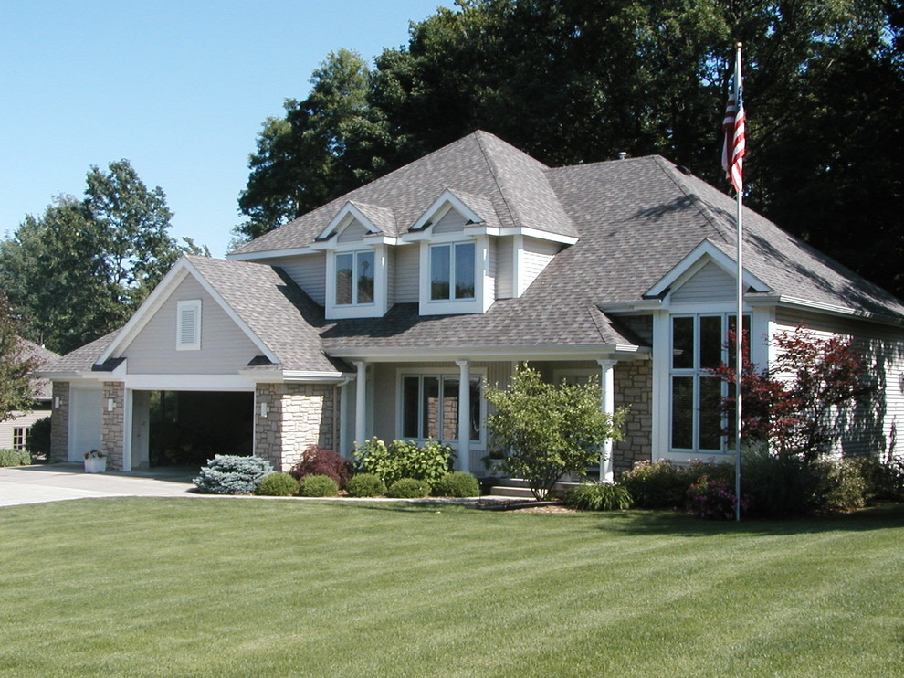 This is an example of a gey and medium sized classic two floor detached house in Grand Rapids with stone cladding, a hip roof and a shingle roof.