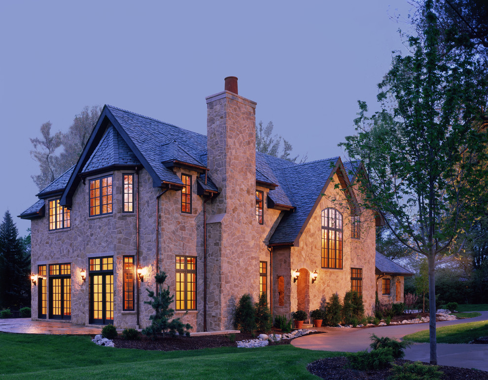 Cette photo montre une grande façade de maison grise chic en pierre à un étage avec un toit à quatre pans.