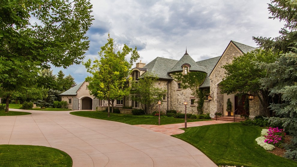 Huge traditional beige two-story stone exterior home idea in Denver with a hip roof