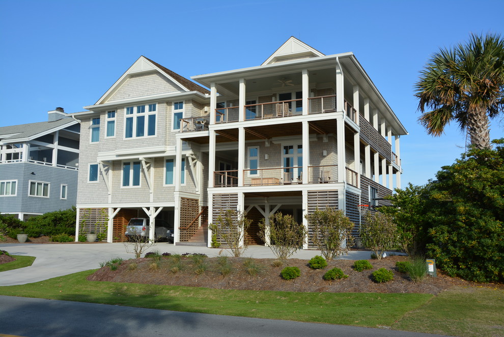 Esempio della facciata di una casa grande beige stile marinaro a tre piani con rivestimento in legno e tetto a capanna