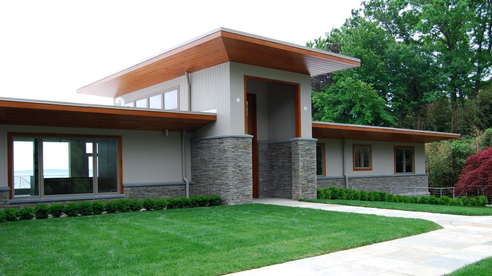 Foto på ett mellanstort funkis grått hus, med två våningar, blandad fasad och platt tak