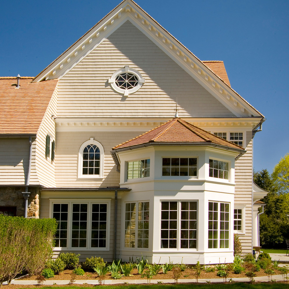 Exemple d'une façade de maison beige chic en bois à un étage et de taille moyenne.