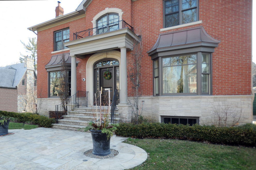 Example of a large classic red two-story brick house exterior design in Toronto