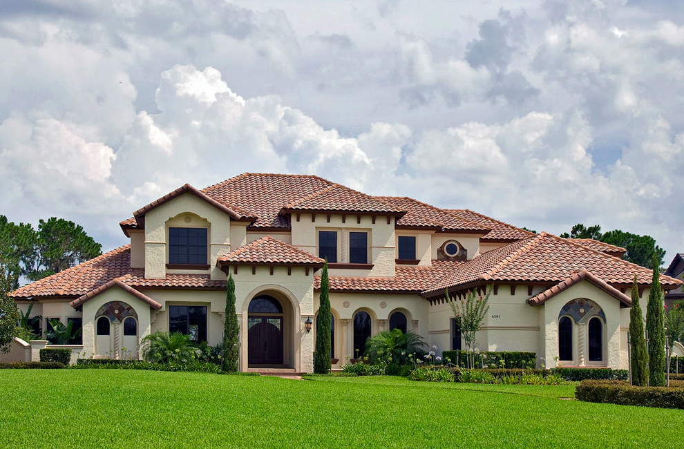This is an example of a large and white mediterranean two floor render detached house in Orlando with a hip roof and a tiled roof.