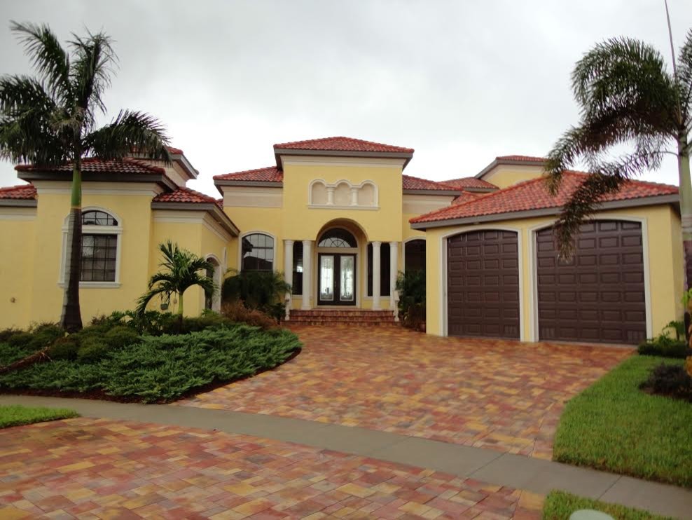 Inspiration for a large tropical yellow one-story stucco house exterior remodel in Orlando with a hip roof and a tile roof