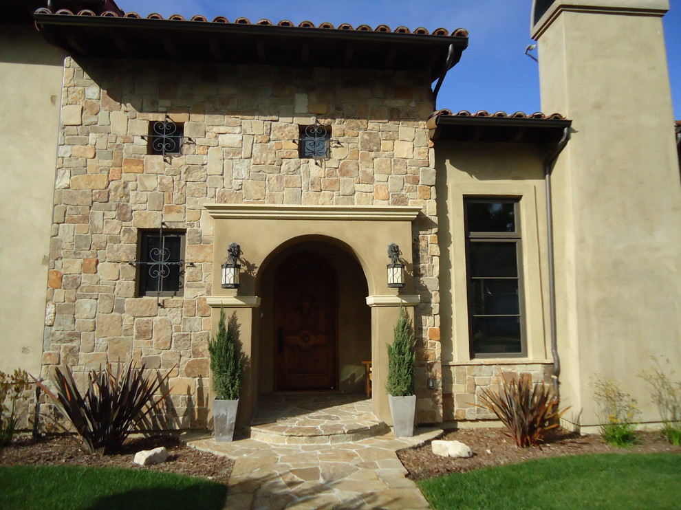 Photo of a beige mediterranean two floor detached house in Los Angeles with mixed cladding and a tiled roof.
