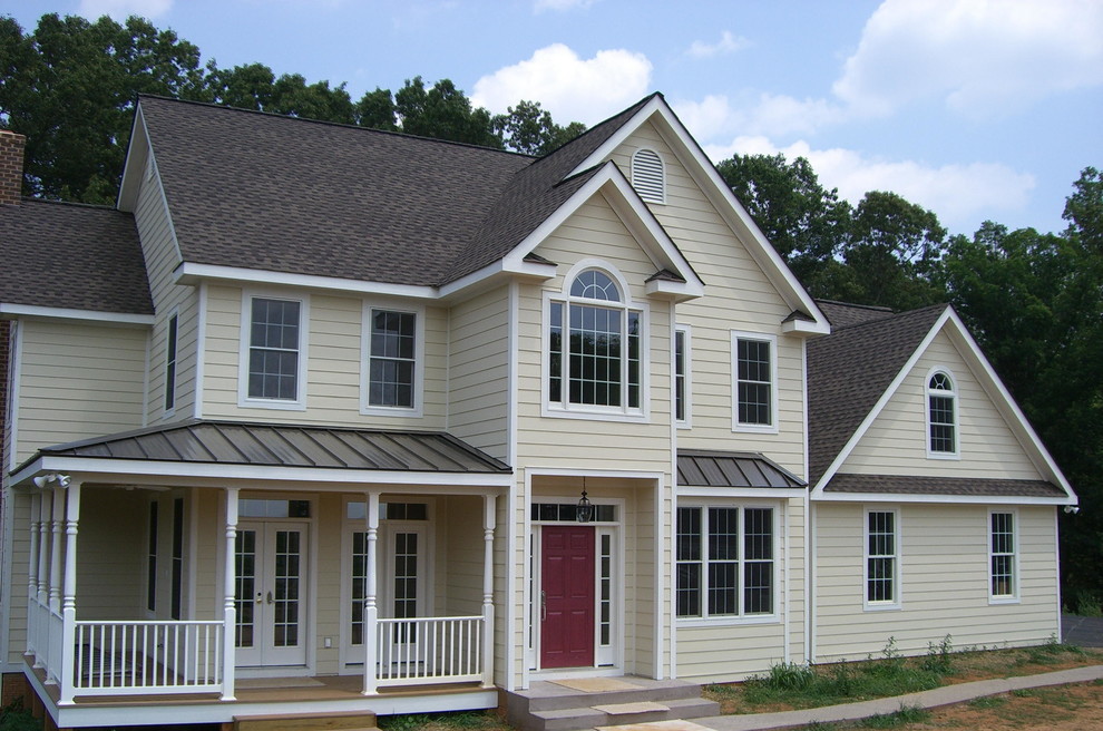 Cette image montre une façade de maison beige traditionnelle de taille moyenne et à un étage avec un revêtement en vinyle et un toit à deux pans.