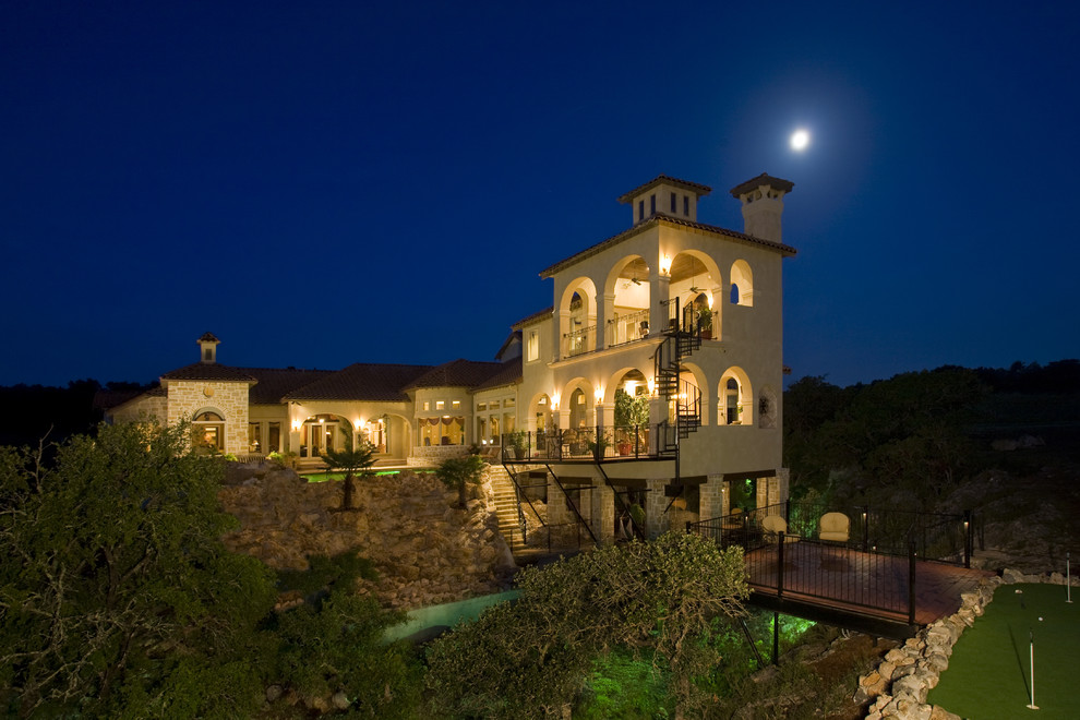 Inspiration for a mid-sized mediterranean beige three-story stucco exterior home remodel in Austin with a hip roof