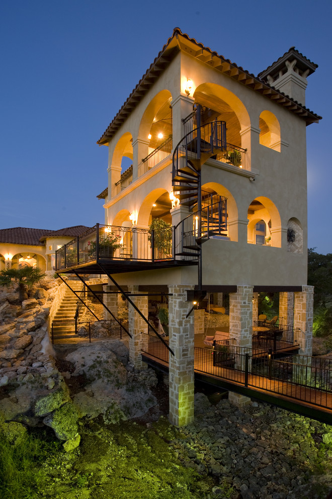 Photo of an expansive and beige mediterranean render house exterior in Austin with three floors and a hip roof.