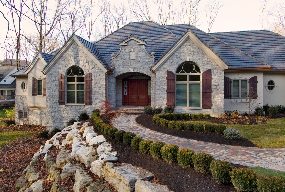 Exemple d'une façade de maison grise chic en pierre de taille moyenne et de plain-pied avec un toit à deux pans.