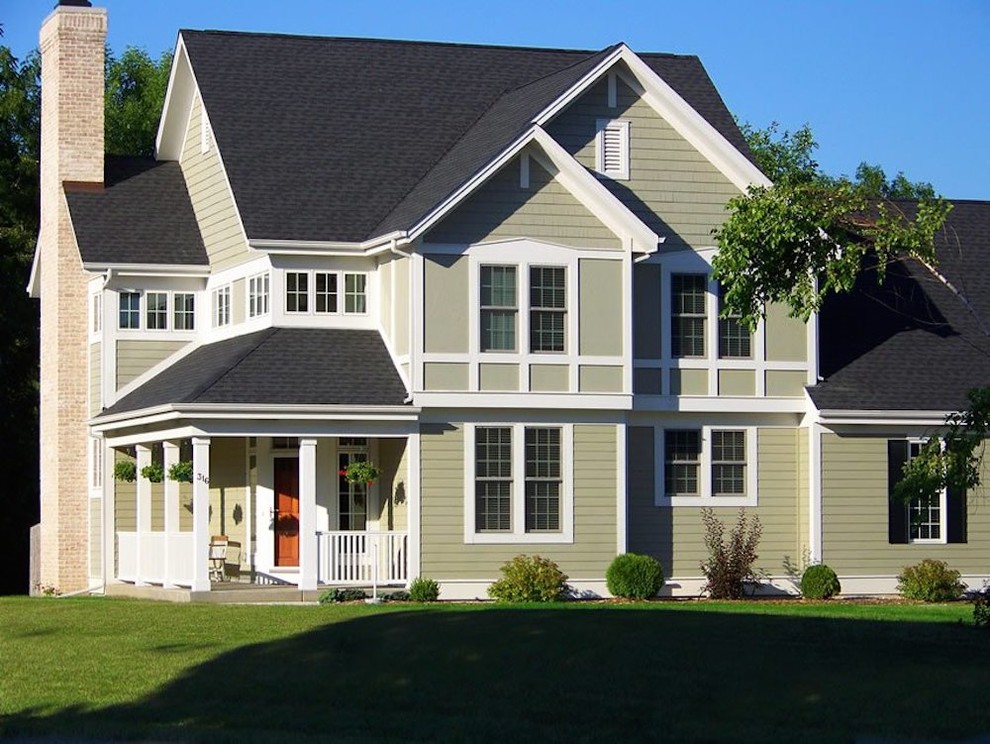 Example of a classic green two-story wood exterior home design in Milwaukee with a shingle roof