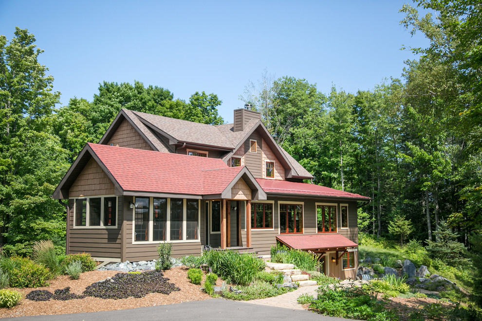 Пример оригинального дизайна: двухэтажный, коричневый частный загородный дом в стиле рустика с комбинированной облицовкой, двускатной крышей и крышей из гибкой черепицы