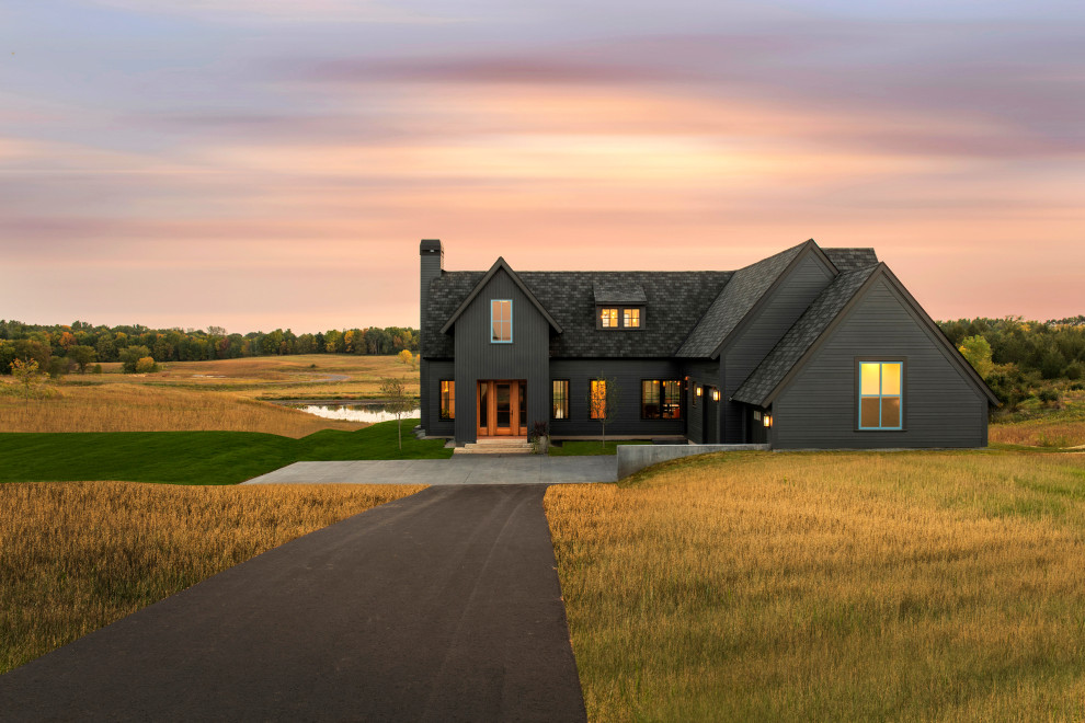 This is an example of a large and black rural detached house in Minneapolis with wood cladding, a pitched roof, a shingle roof and a black roof.