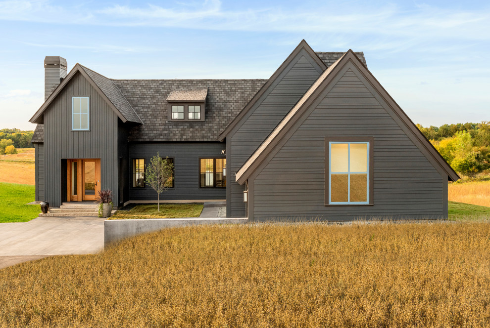 Idée de décoration pour une grande façade de maison noire champêtre avec un toit à deux pans et un toit noir.