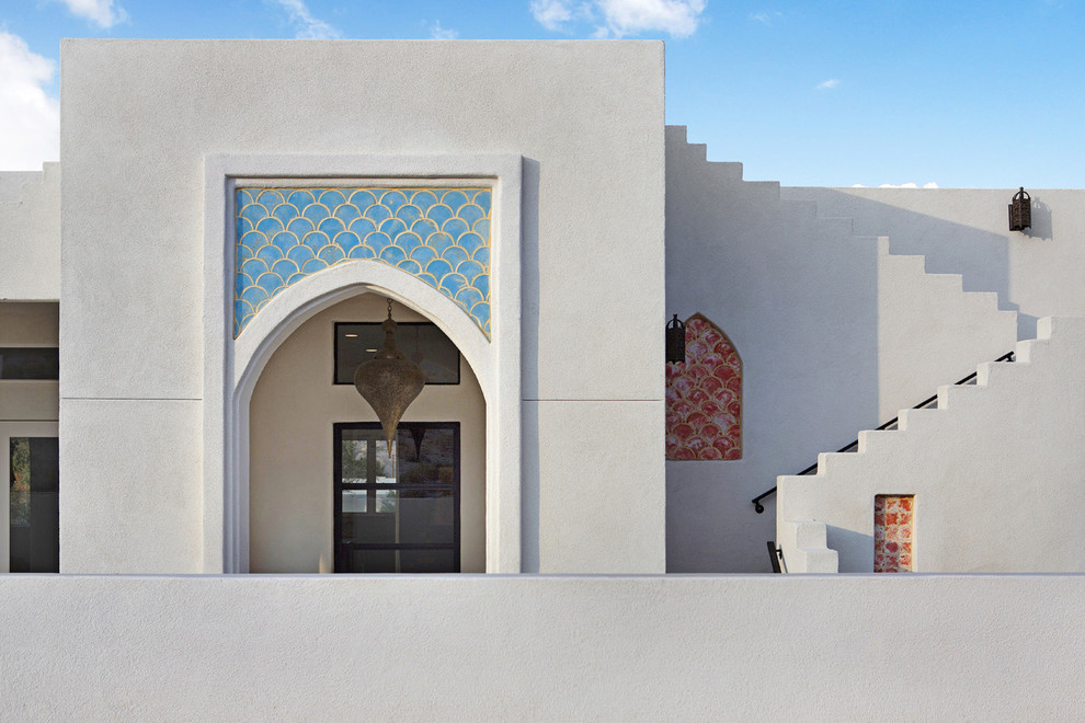 Inspiration pour une grande façade de maison blanche méditerranéenne en adobe de plain-pied avec un toit plat et un toit en tuile.