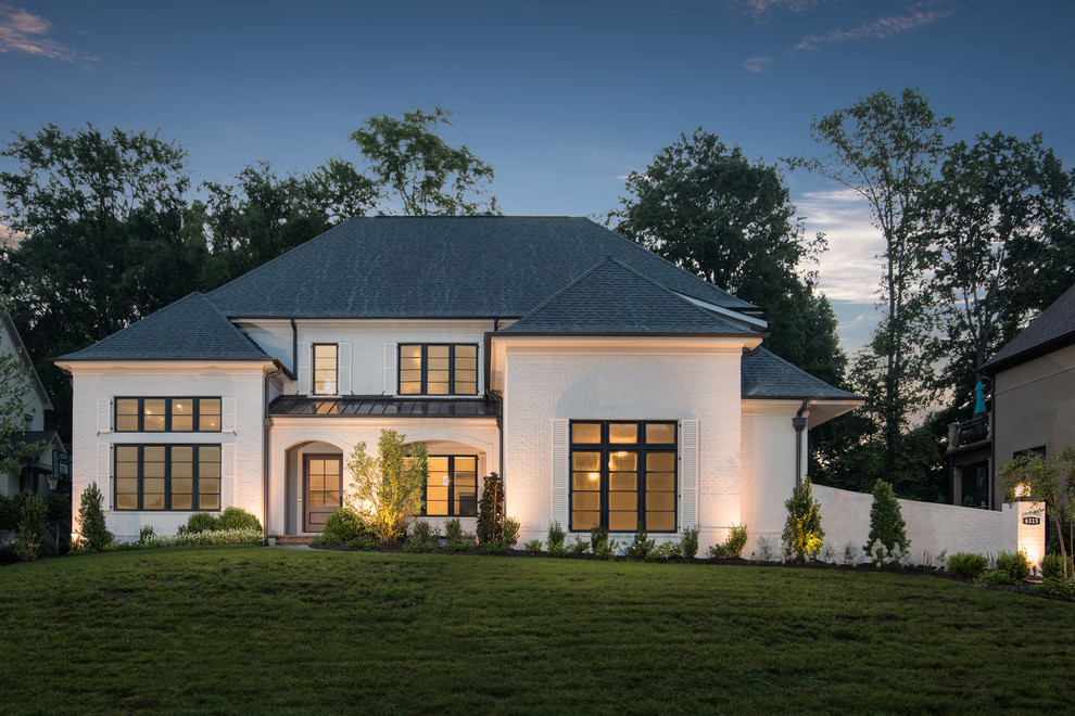 Стильный дизайн: двухэтажный, кирпичный, белый частный загородный дом в стиле фьюжн с вальмовой крышей и крышей из смешанных материалов - последний тренд
