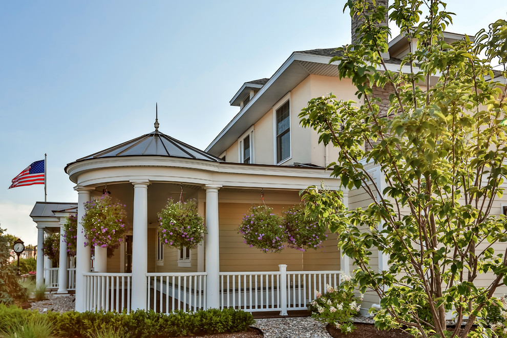 Esempio della facciata di una casa grande beige classica a due piani con rivestimenti misti e tetto a padiglione